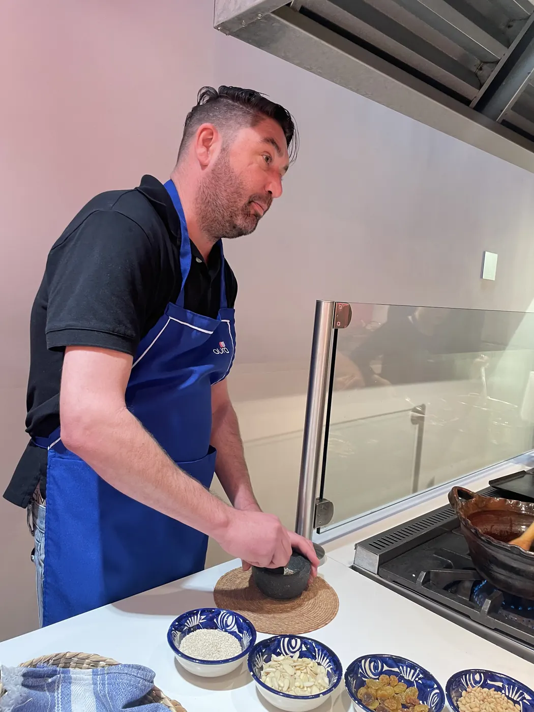 Christopher grinding spices with a stone molcajete beside little talavera bowls of rice, garlic and raisins in a Mexico City kitchen.